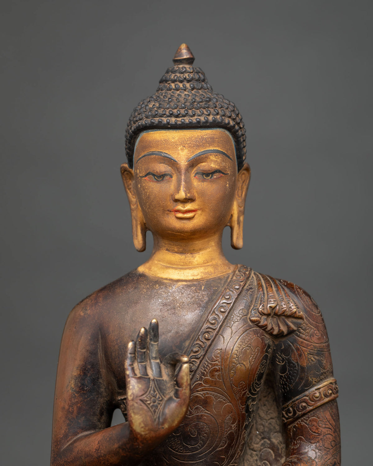 Handcrafted oxidized copper Amoghasiddhi Buddha idol showing 24K gold painted face and Abhaya Mudra.