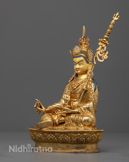 handcrafted Guru Rinpoche statue holding a 9-pronged vajra, skull cup with vase, and three-kapala trident, showing intricate jewelry and Dhonka robe carvings