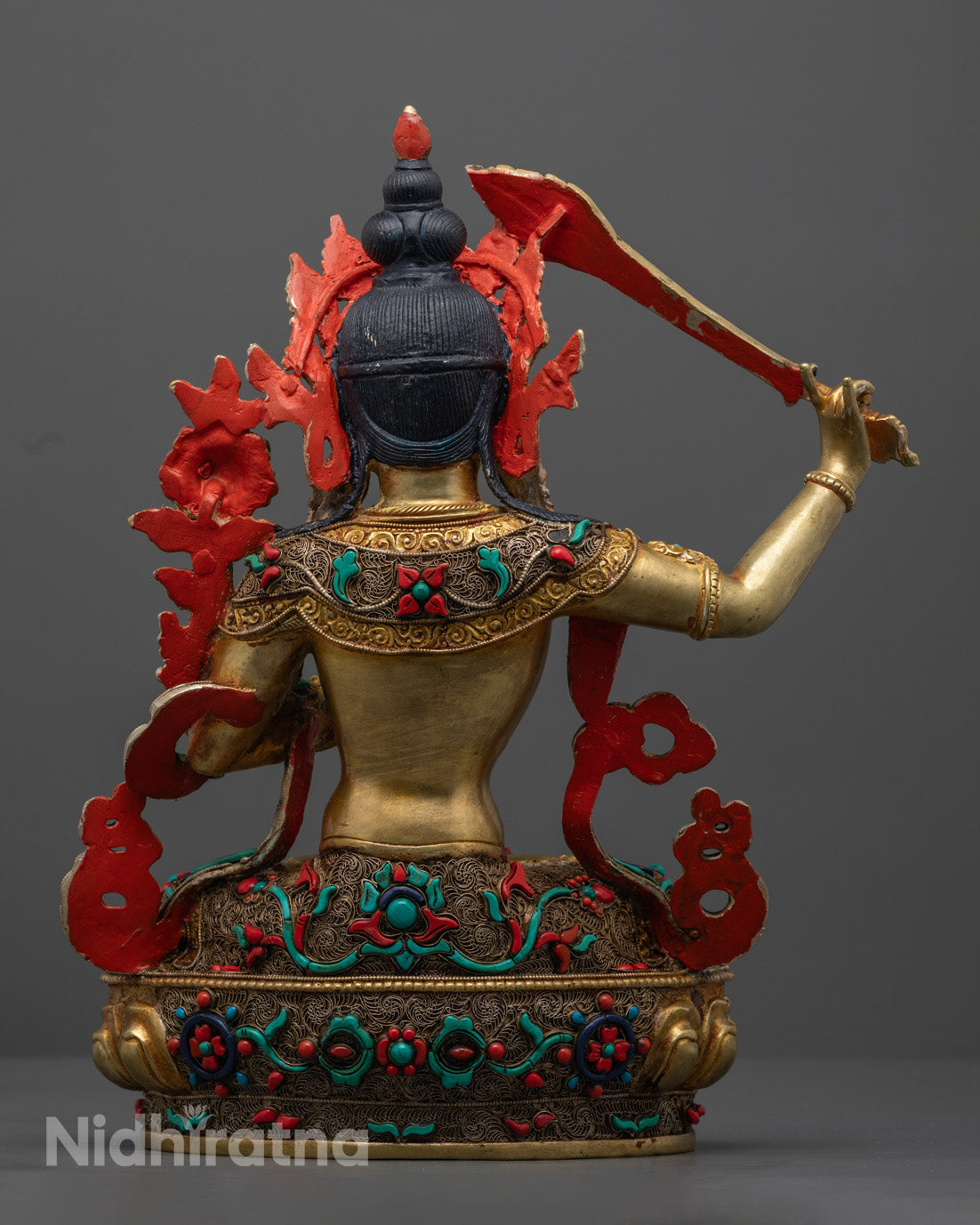 The Manjushri statue, focusing on the expressive face, lotus flower, and sword, representing clarity and insight in Buddhist tradition