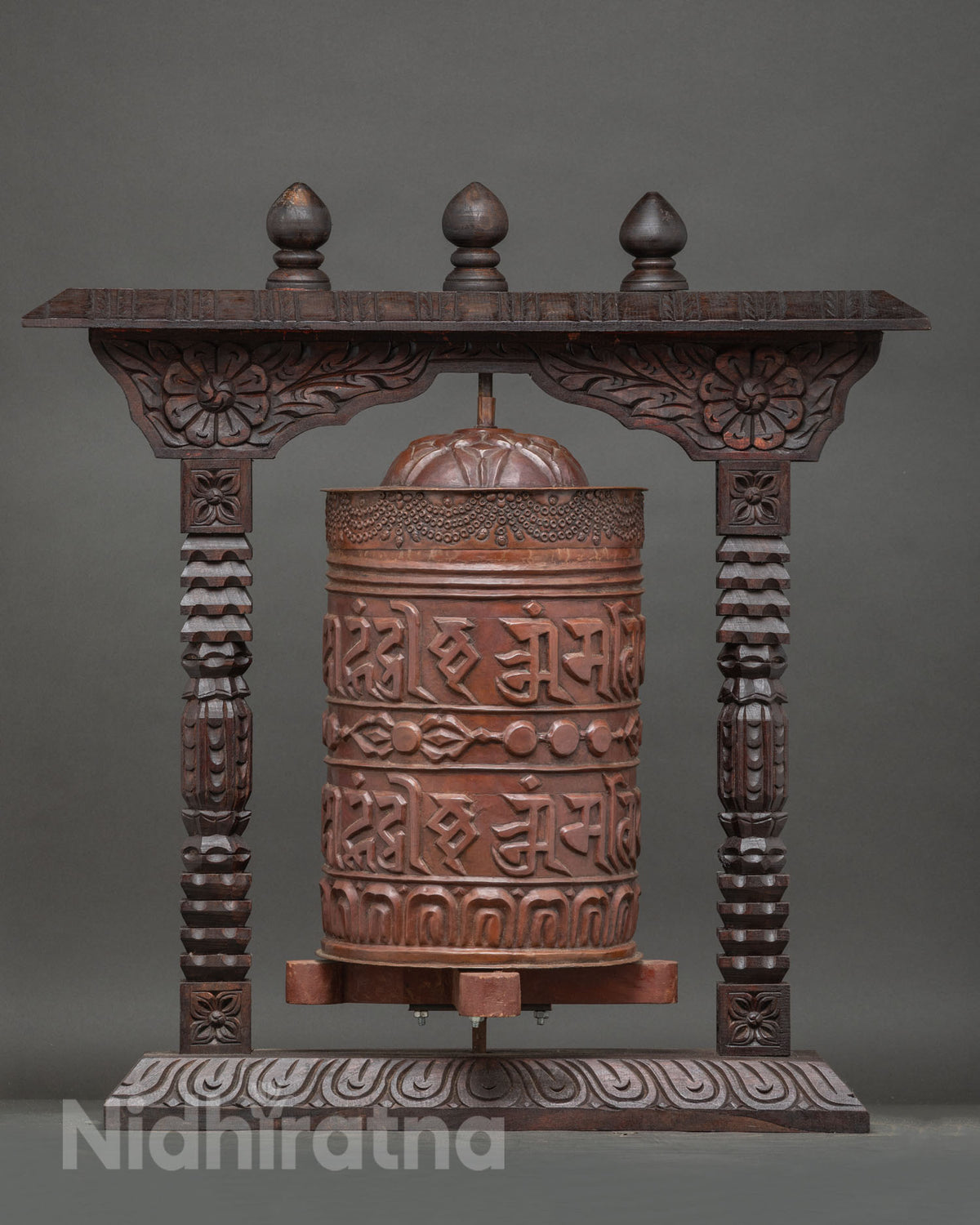 Intricately carved wooden prayer wheel frame with floral motifs columns and ornamental details.