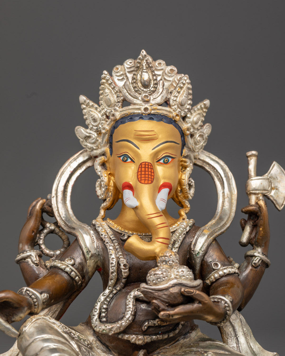 intricately carved silver-plated crown and ornate jewelry on handmade Ganesh idol