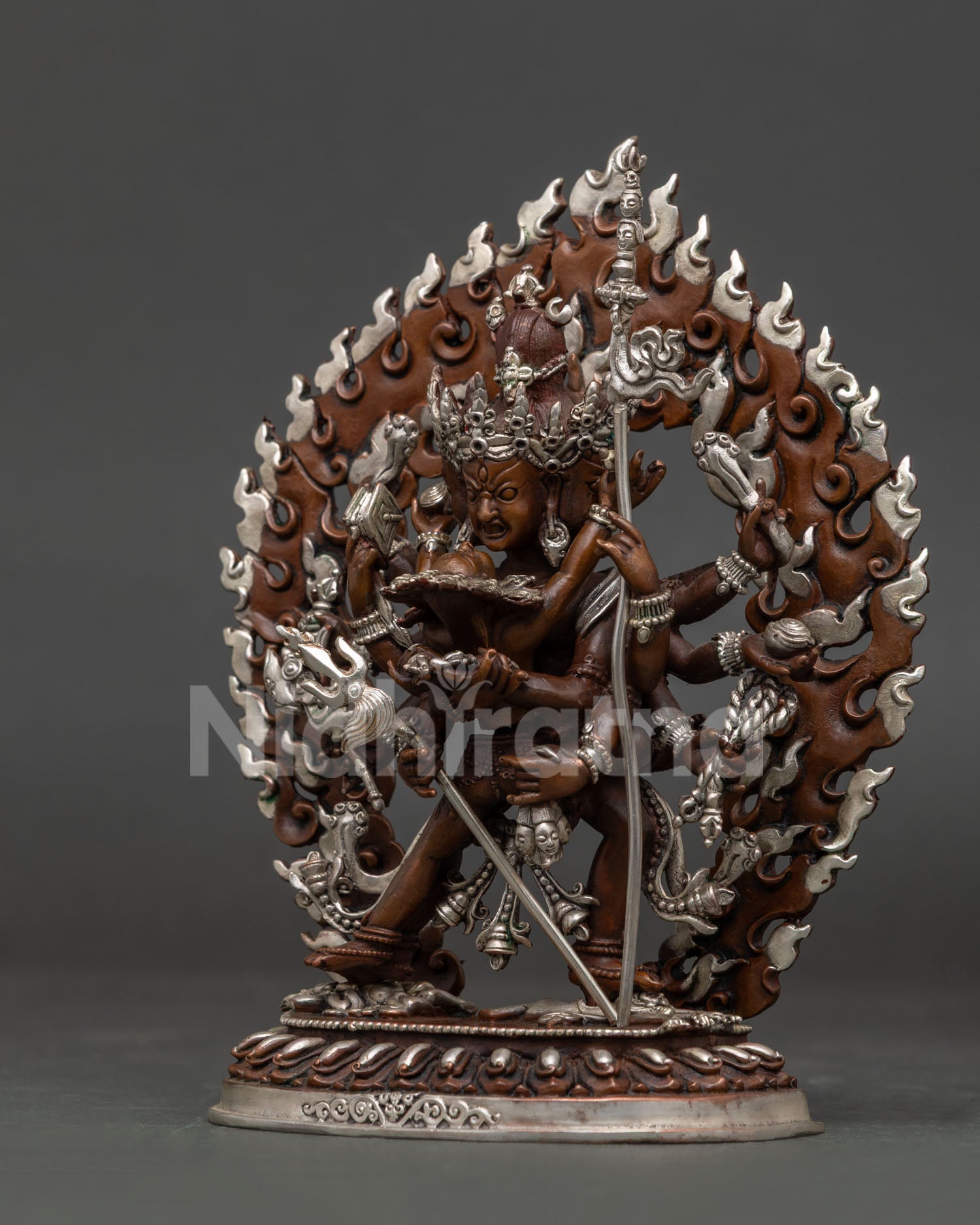 Kalachakra statue with lotus throne subduing figure and blazing halo.