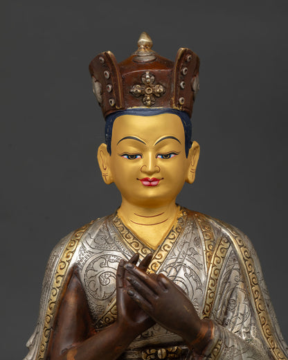 Karmapa statue seated on pedestal with black ritual crown and gold painted face.