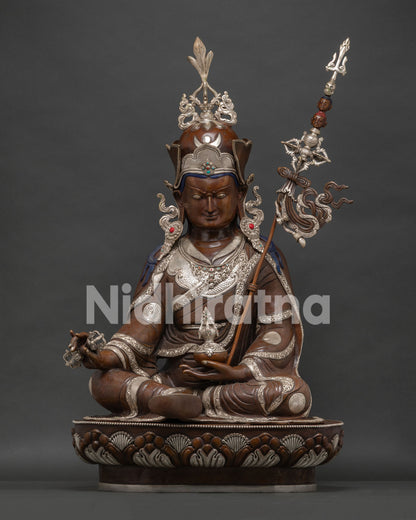 Large Guru Rinpoche statue with silver plating and oxidized copper finish on lotus throne.