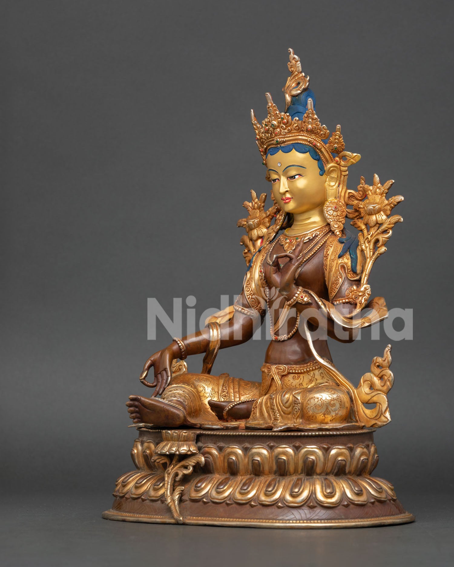 left profile of green tara statue with lotus seat and gold painted serene expression