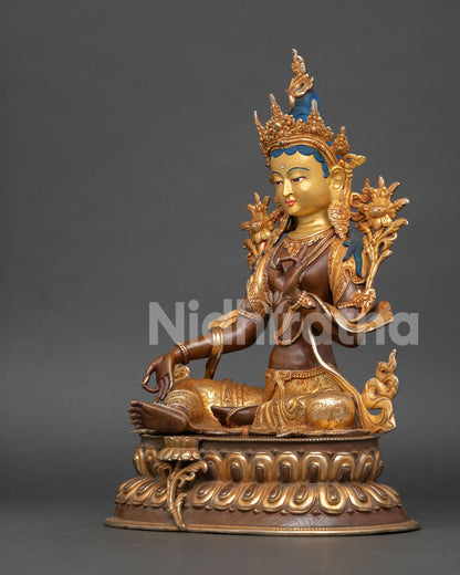 left profile of green tara statue with lotus seat and gold painted serene expression