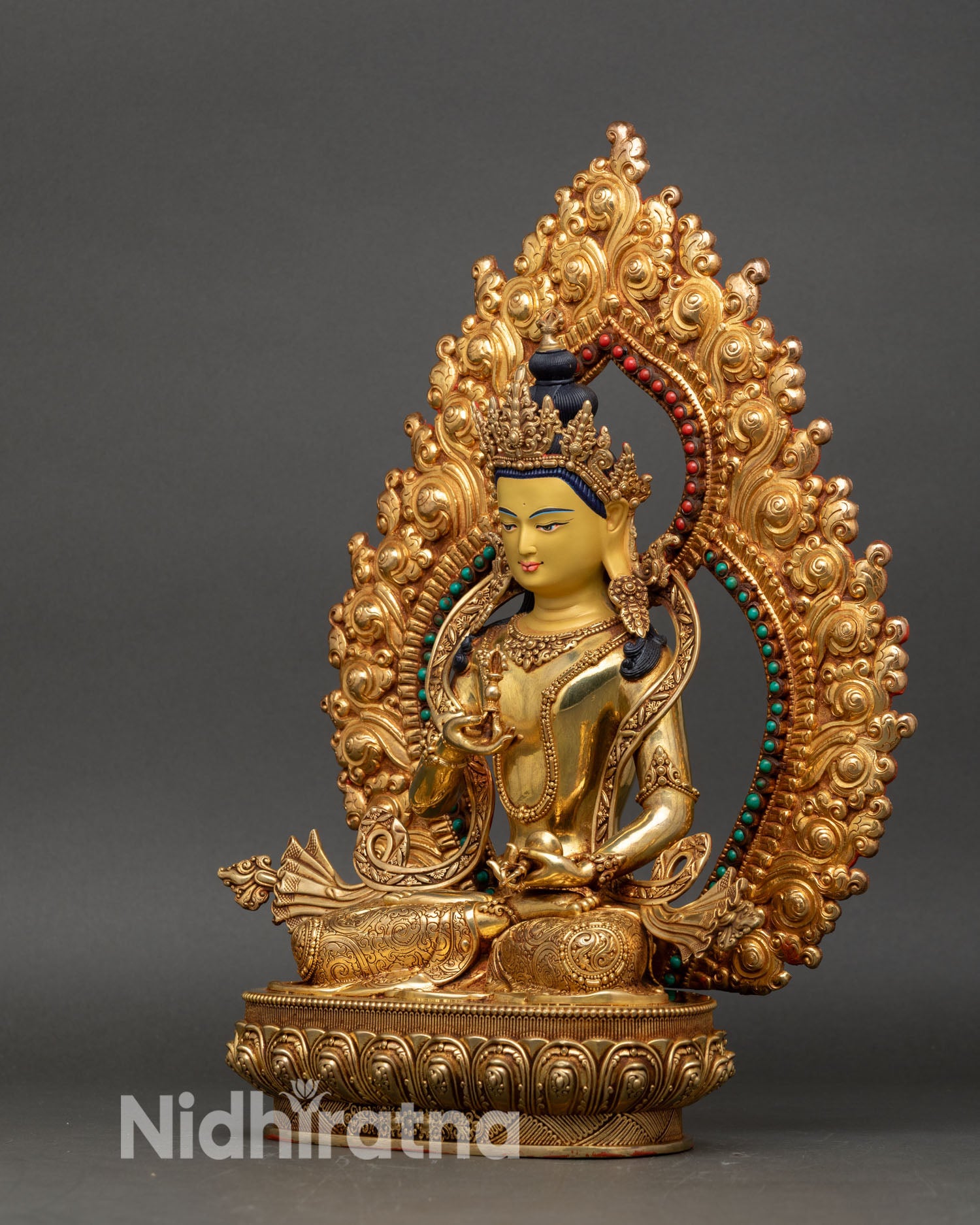 left profile of vajrasattva statue with turquoise and coral inlaid torana and gold finish