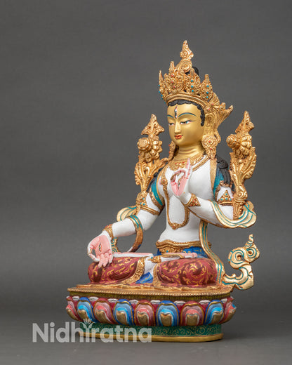 left profile of white tara statue, white-toned body with gold-gilded robes and crown