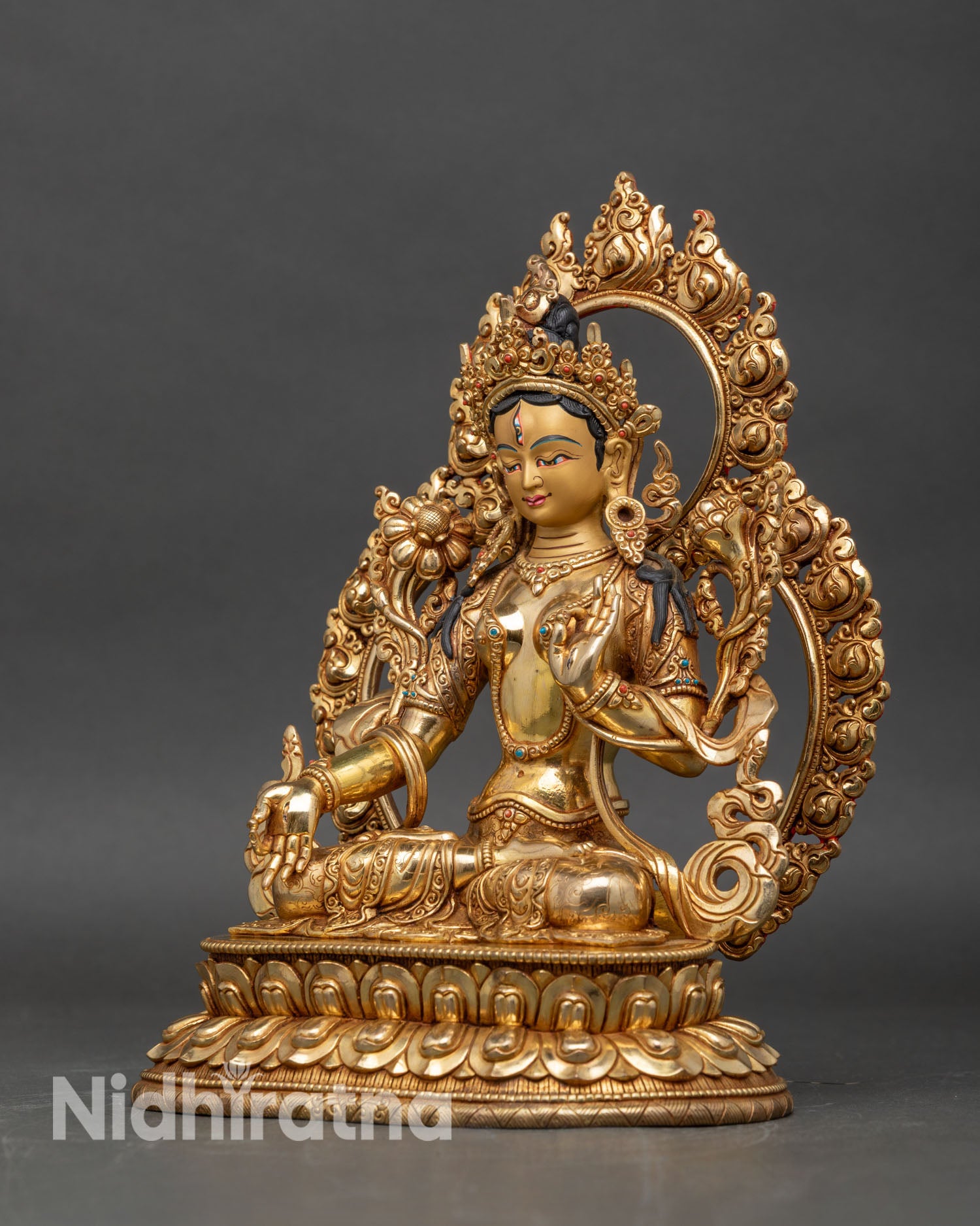 Left profile of White Tara statue, lotus stem in hand and detailed jewelry visible