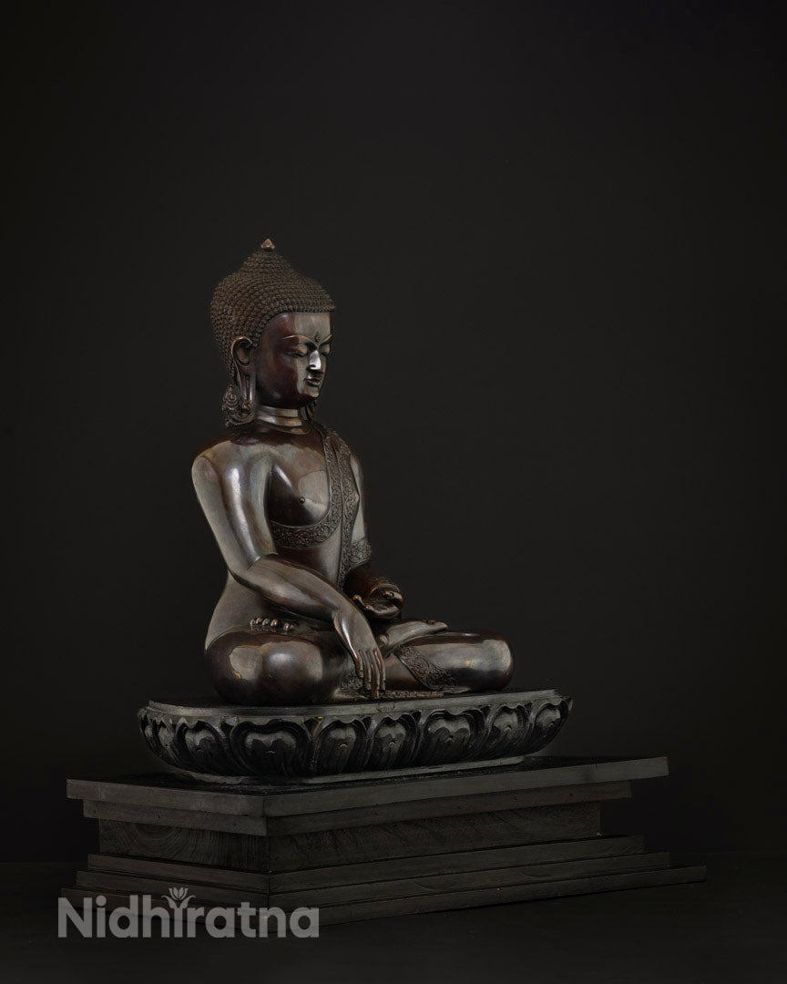 Left side profile of copper Shakyamuni Buddha statue seated on carved lotus pedestal