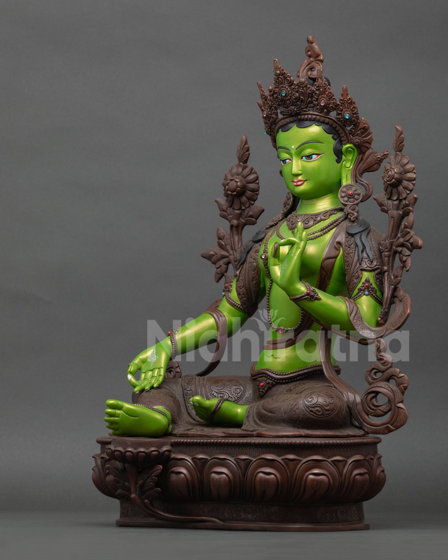 left side profile of green tara statue with oxidized copper body and floral scrollwork