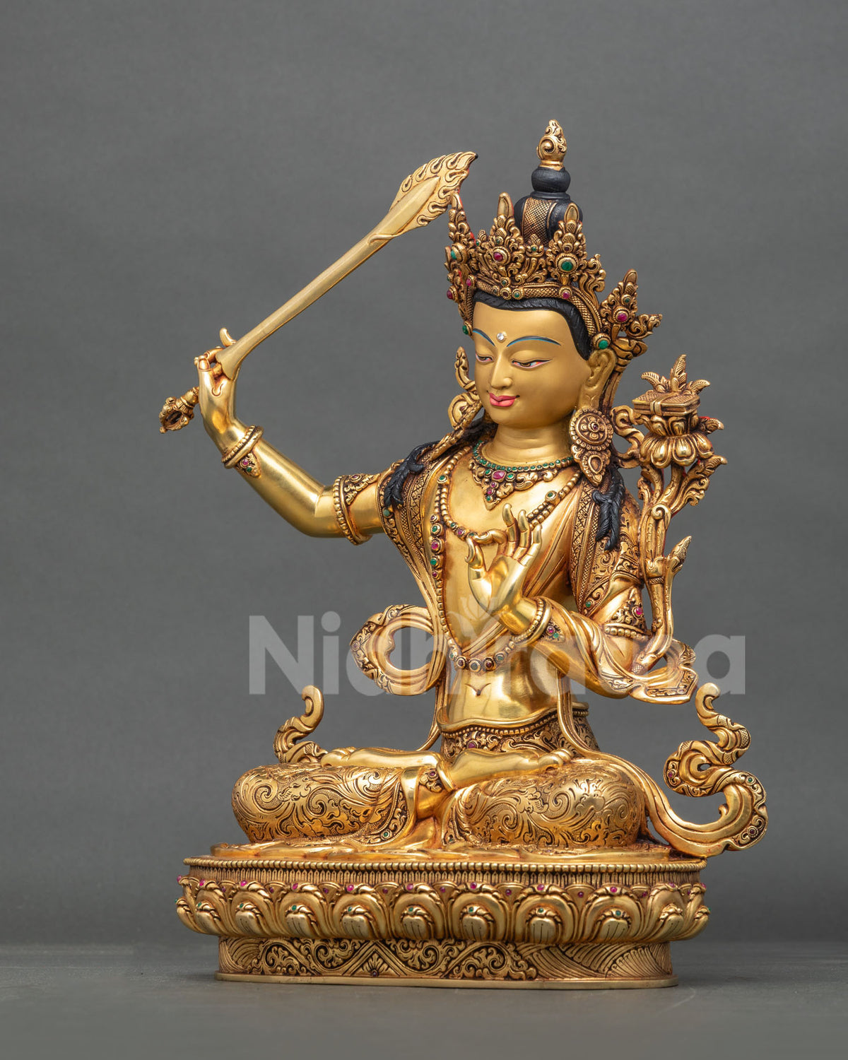 Left side profile view of Manjushri statue showing flaming sword and lotus pedestal.