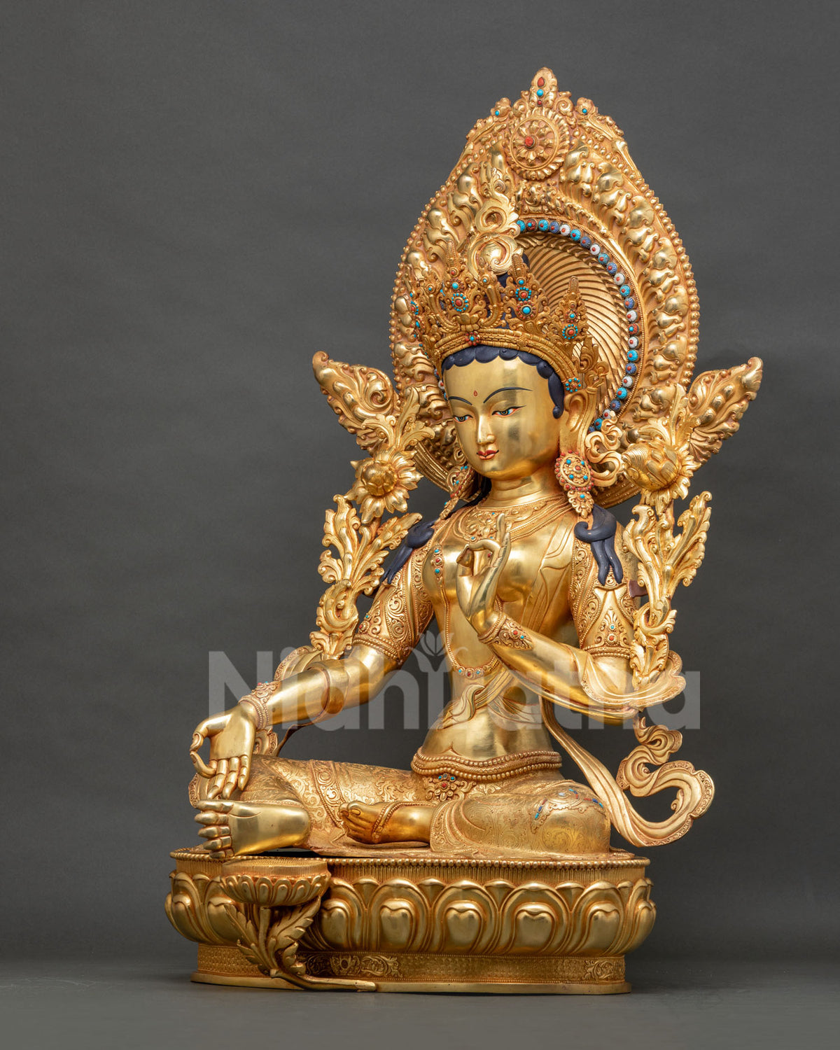 Left side view of Green Tara statue in lalitasana with varada mudra