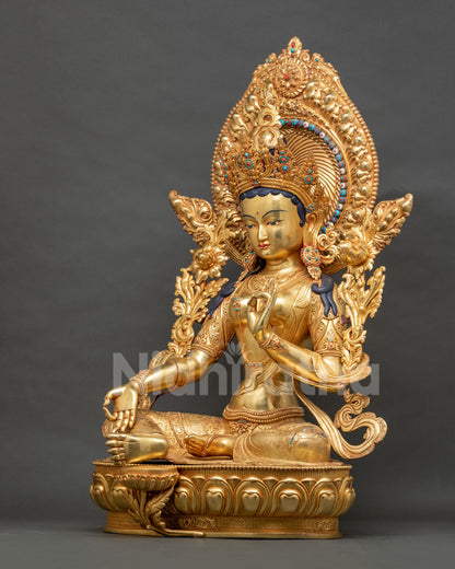 Left side view of Green Tara statue in lalitasana with varada mudra
