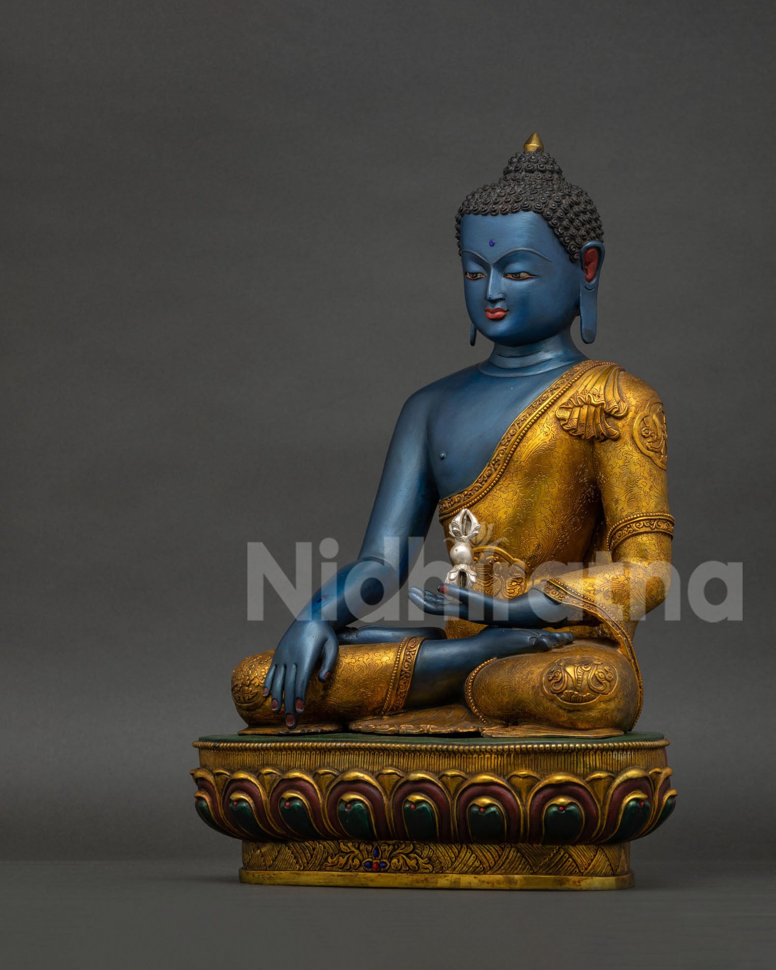 Left side view of Akshobhya Buddha statue with silver plated vajra and floral robe carving