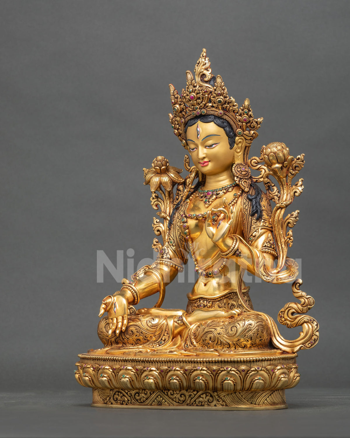 Left side view of Buddhist White Tara statue from Nepal with lotus flowers and gold gilding