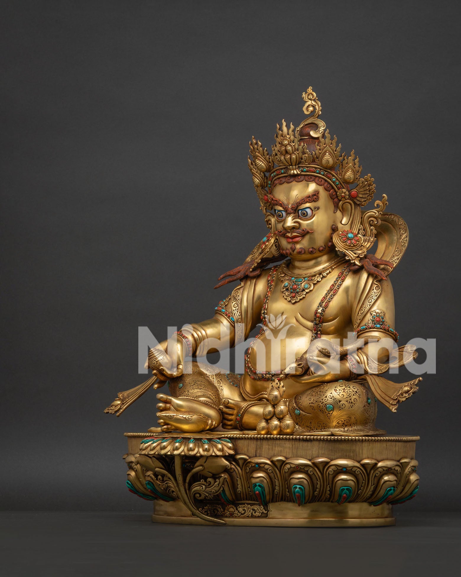 Left side view of gold Dzambhala statue holding the jewel-spitting mongoose.