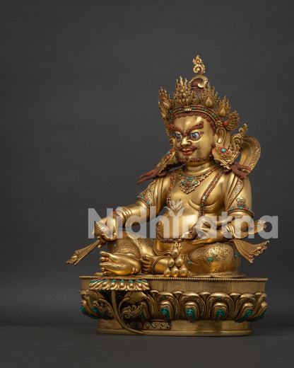 Left side view of gold Dzambhala statue holding the jewel-spitting mongoose.