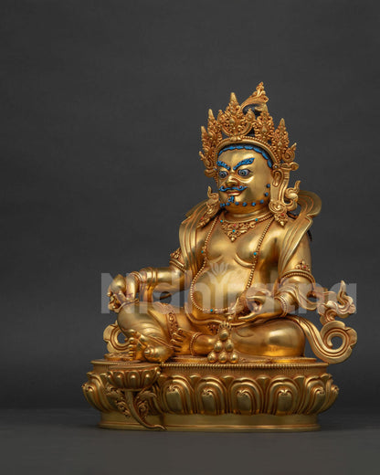 Left side view of gold fire-gilded Dzambhala statue on carved lotus base