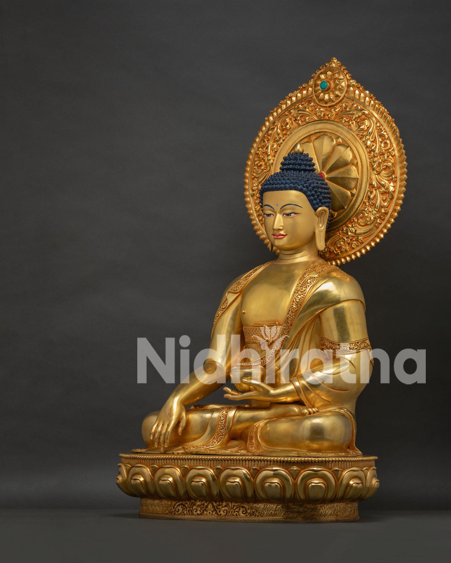 Left side view of gold gilded Buddha statue showing seated posture and intricate aureole backdrop
