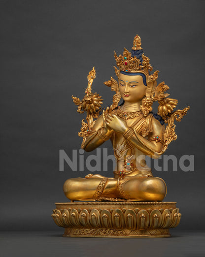 Left side view of gold gilded Manjushri statue seated on a lotus base