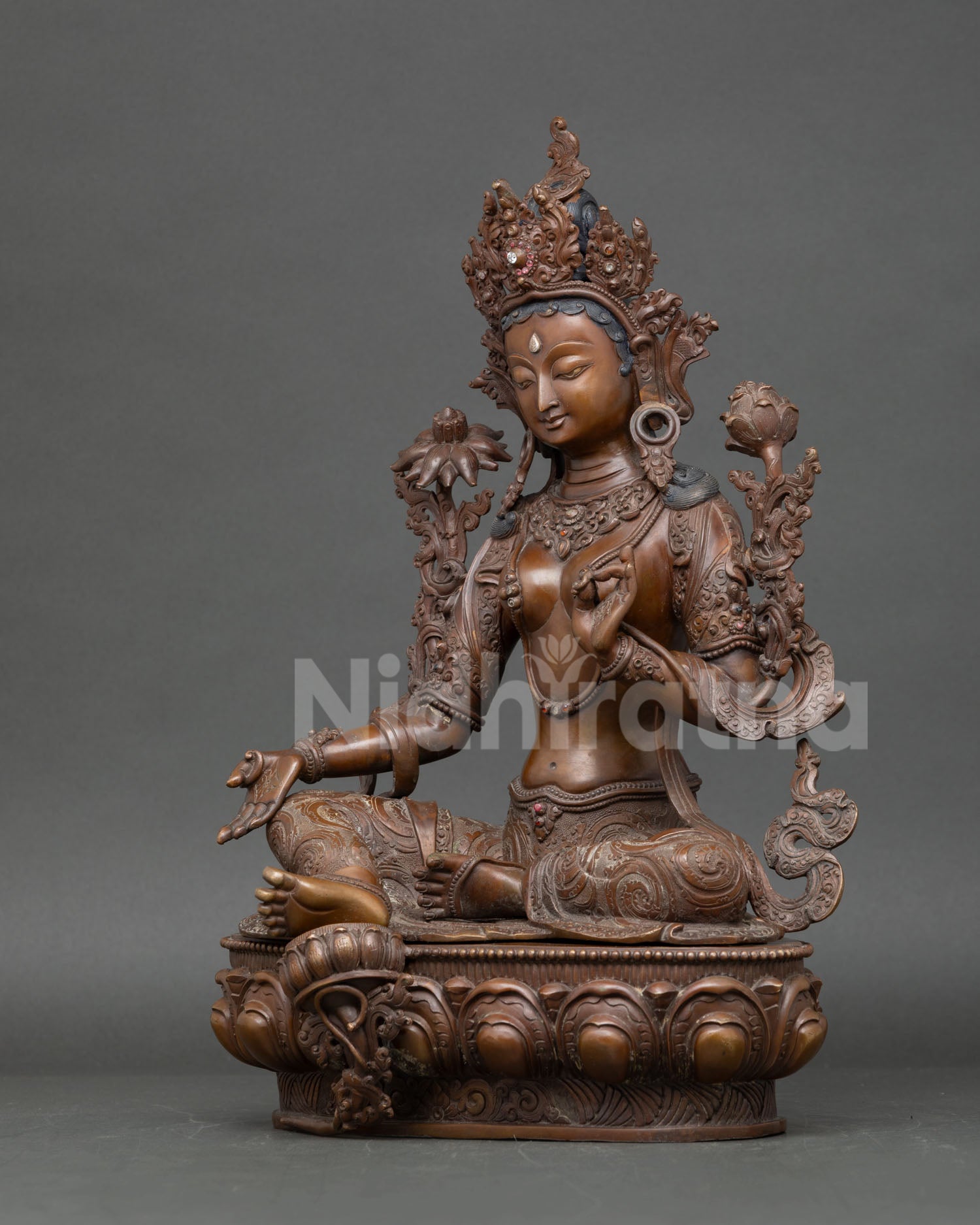 Left side view of Green Tara sculpture with detailed garments and lotus seat
