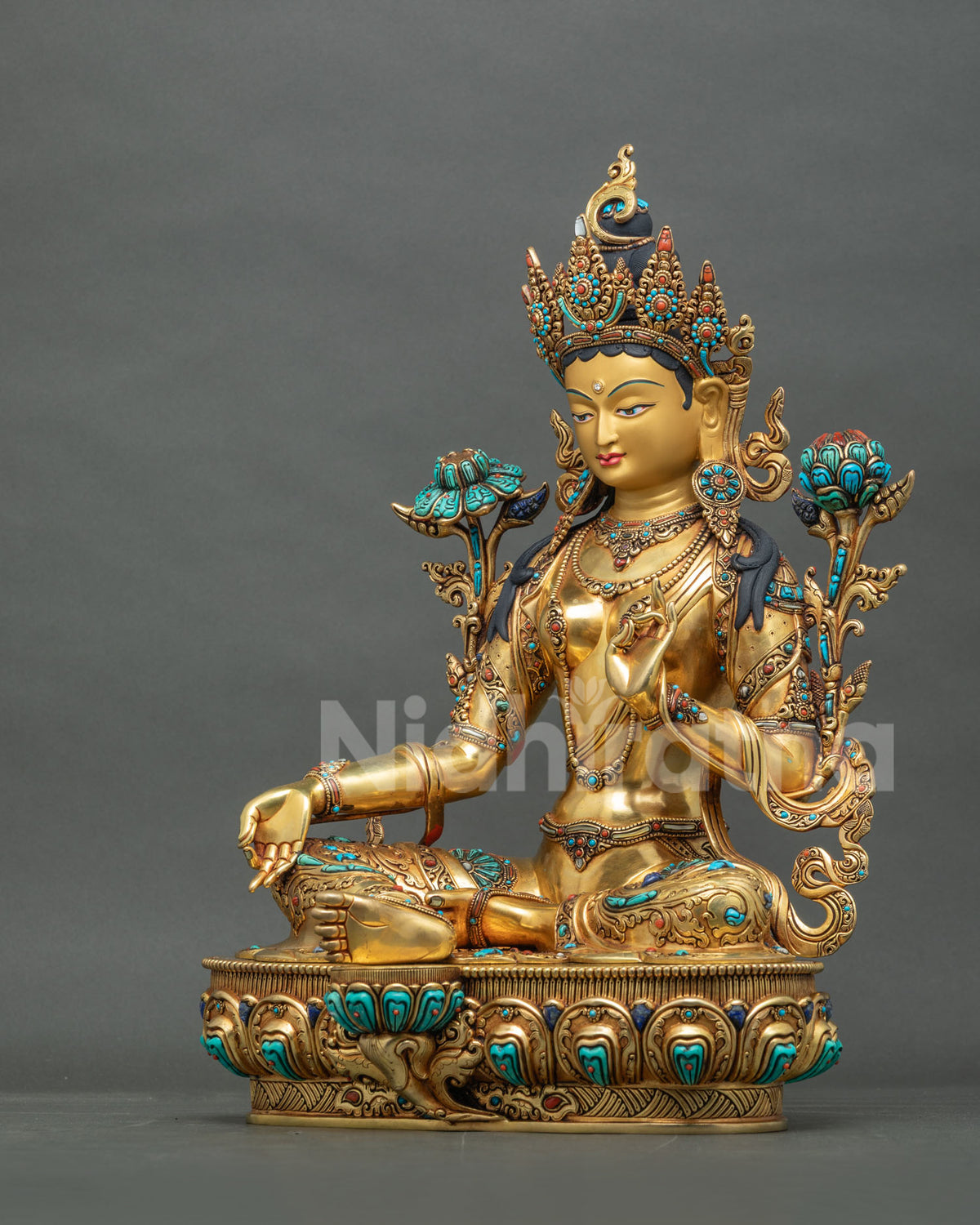Left side view of Green Tara statue holding utpala lotus, handcrafted in Nepal from gilded copper