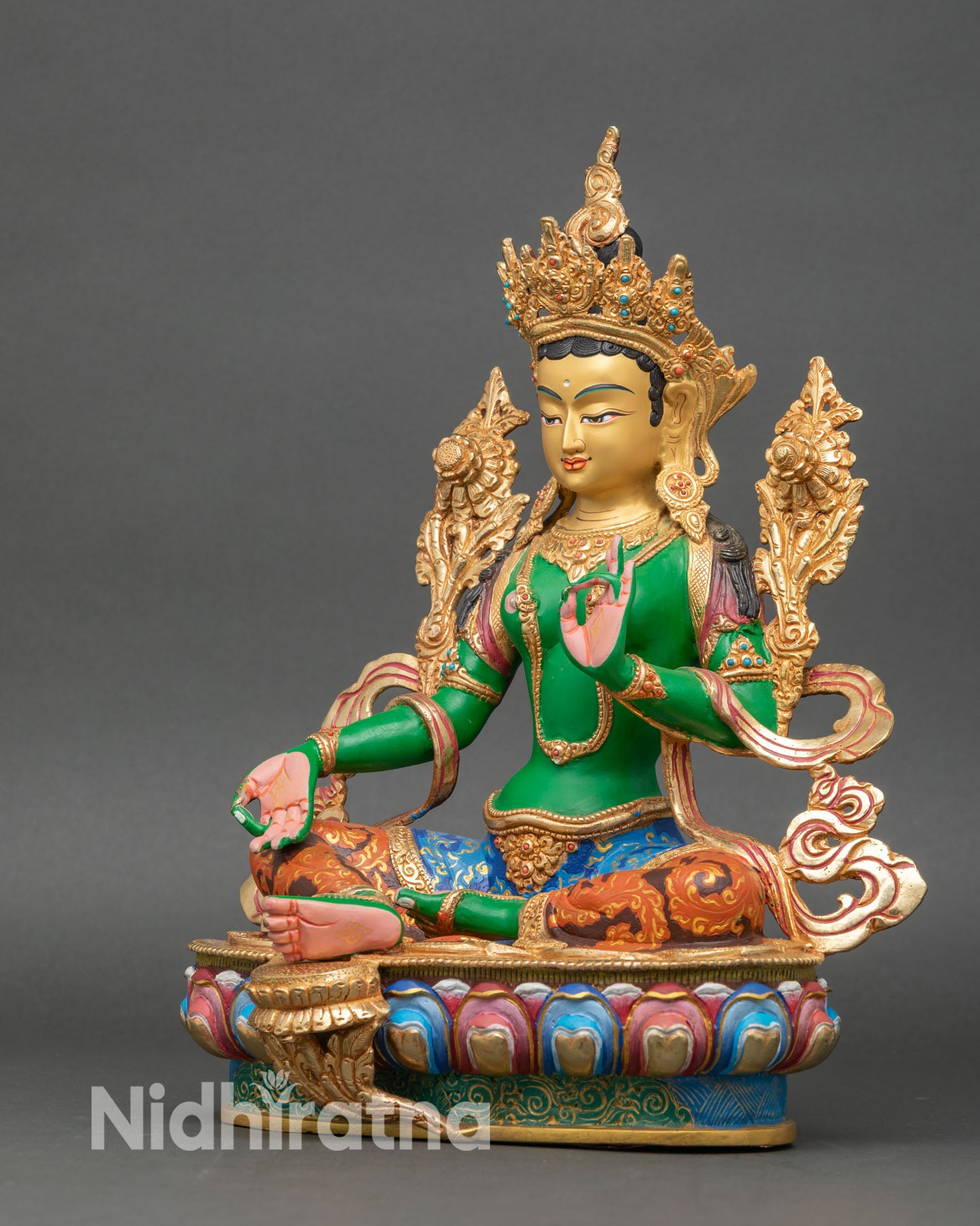 Left side view of Green Tara statue, showcasing multicolor garments and gold-accented details