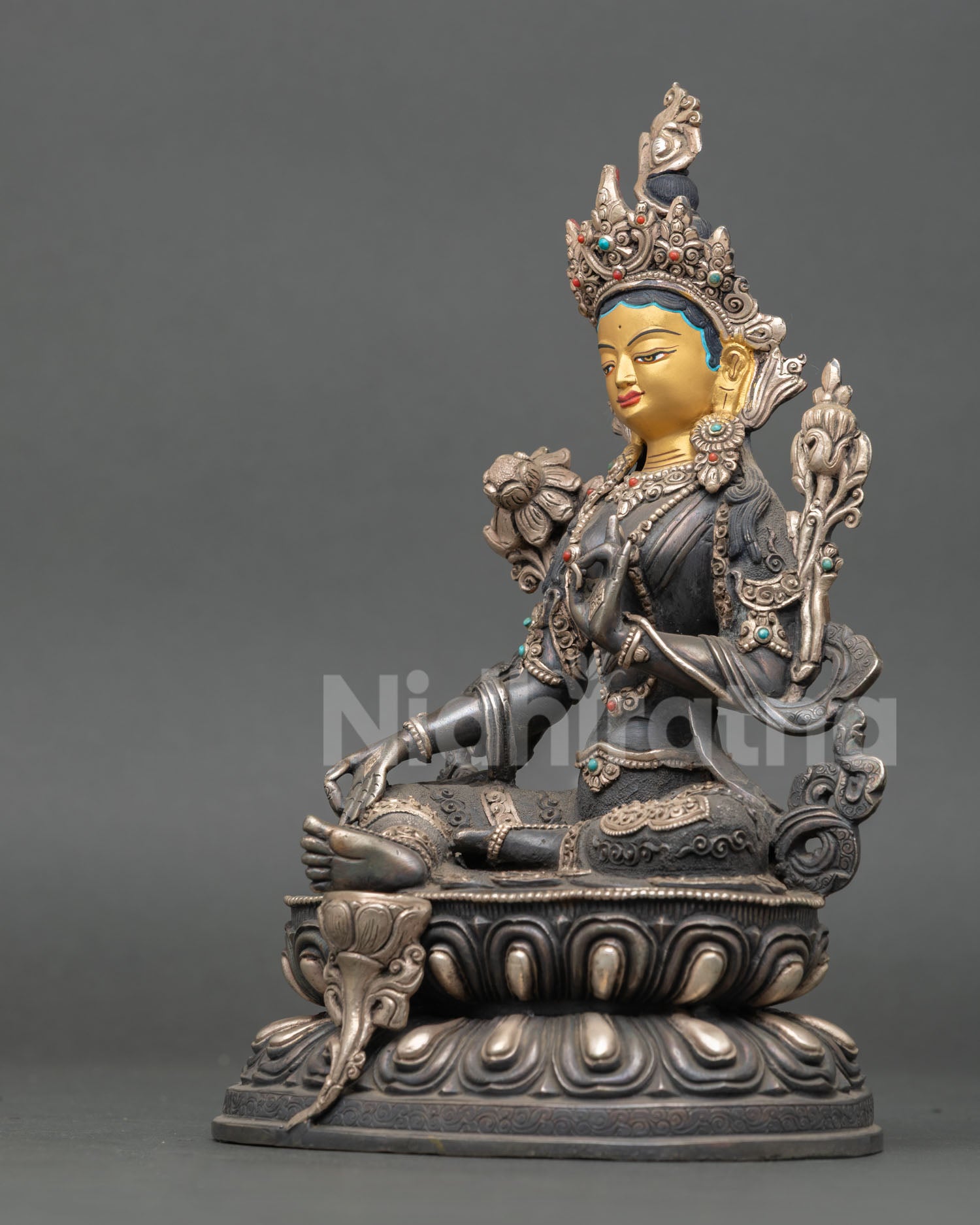 left side view of green tara statue with varada mudra and oxidized copper body