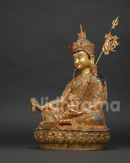 Left side view of Guru Rinpoche statue holding kapala and khatvanga staff