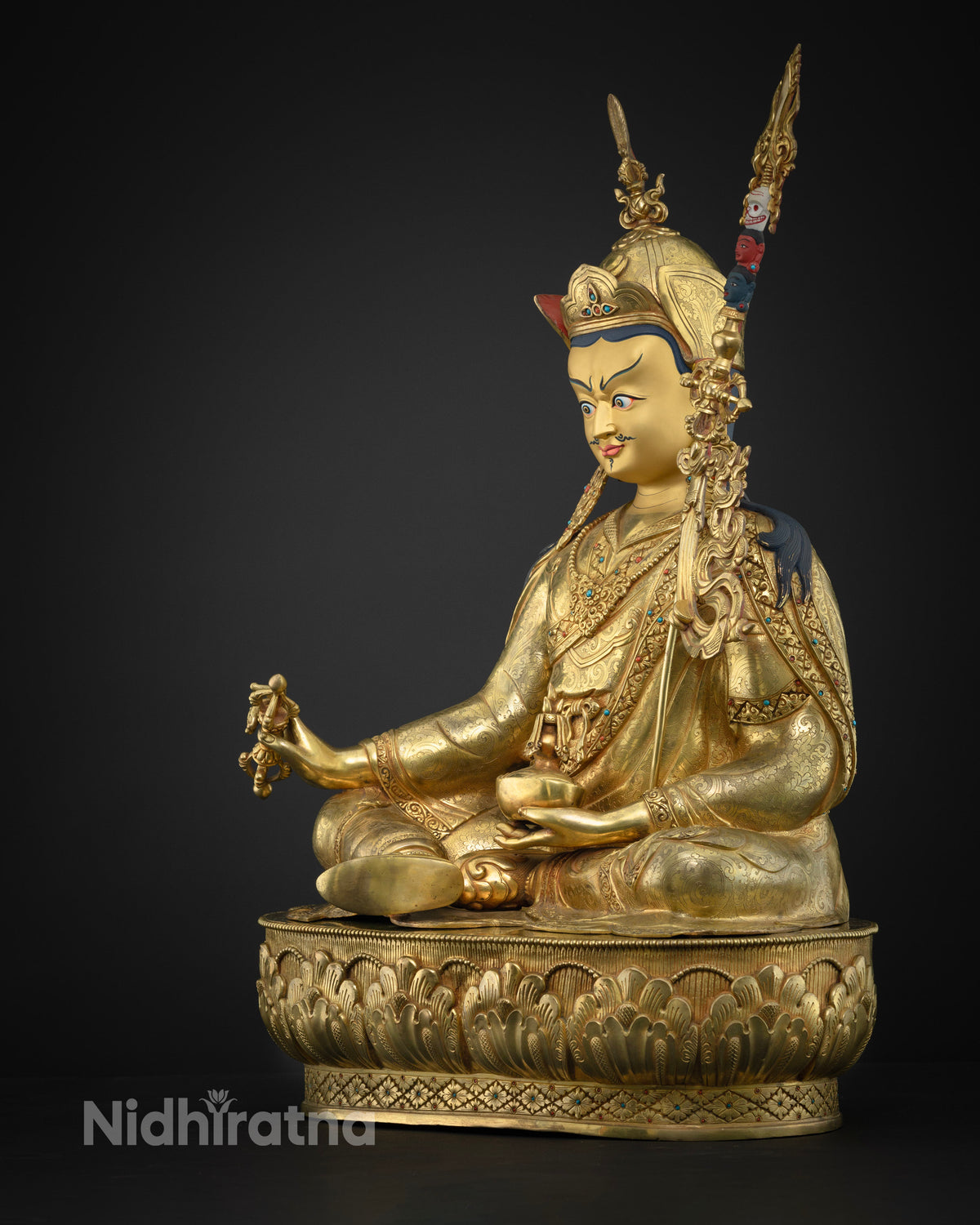 Left side view of Guru Rinpoche statue with kapala skull cup and vajra in gold fire-gilded copper