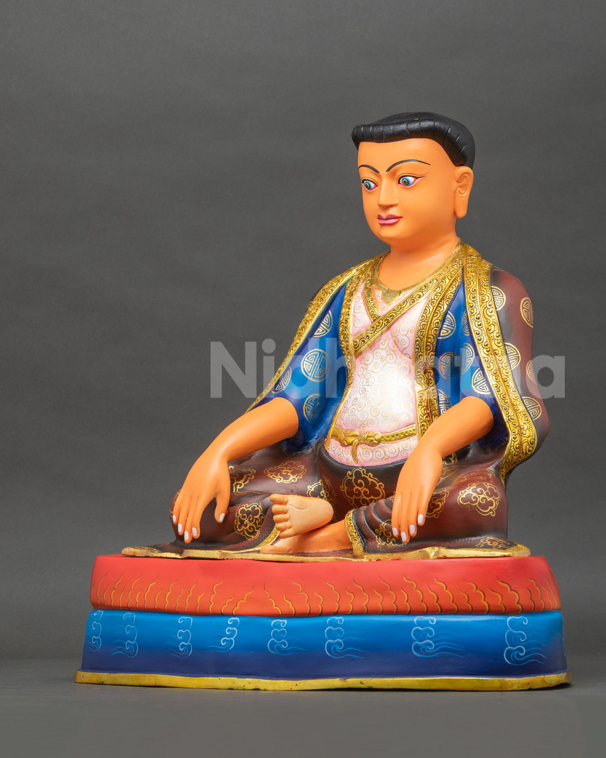 left side view of handcrafted marpa buddhist master statue with gold cloud robes and pedestal