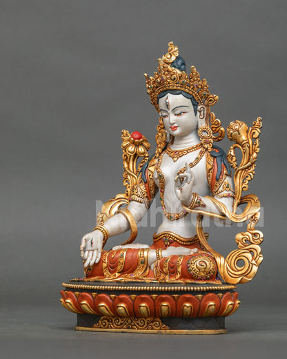left side view of handcrafted white tara sculpture seated on a red and gold lotus base
