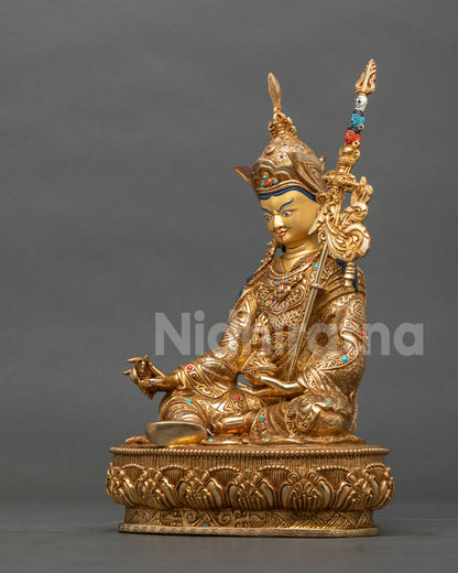 Left side view of Padmasambhava statue seated in royal posture on a lotus base, fire-gilded copper