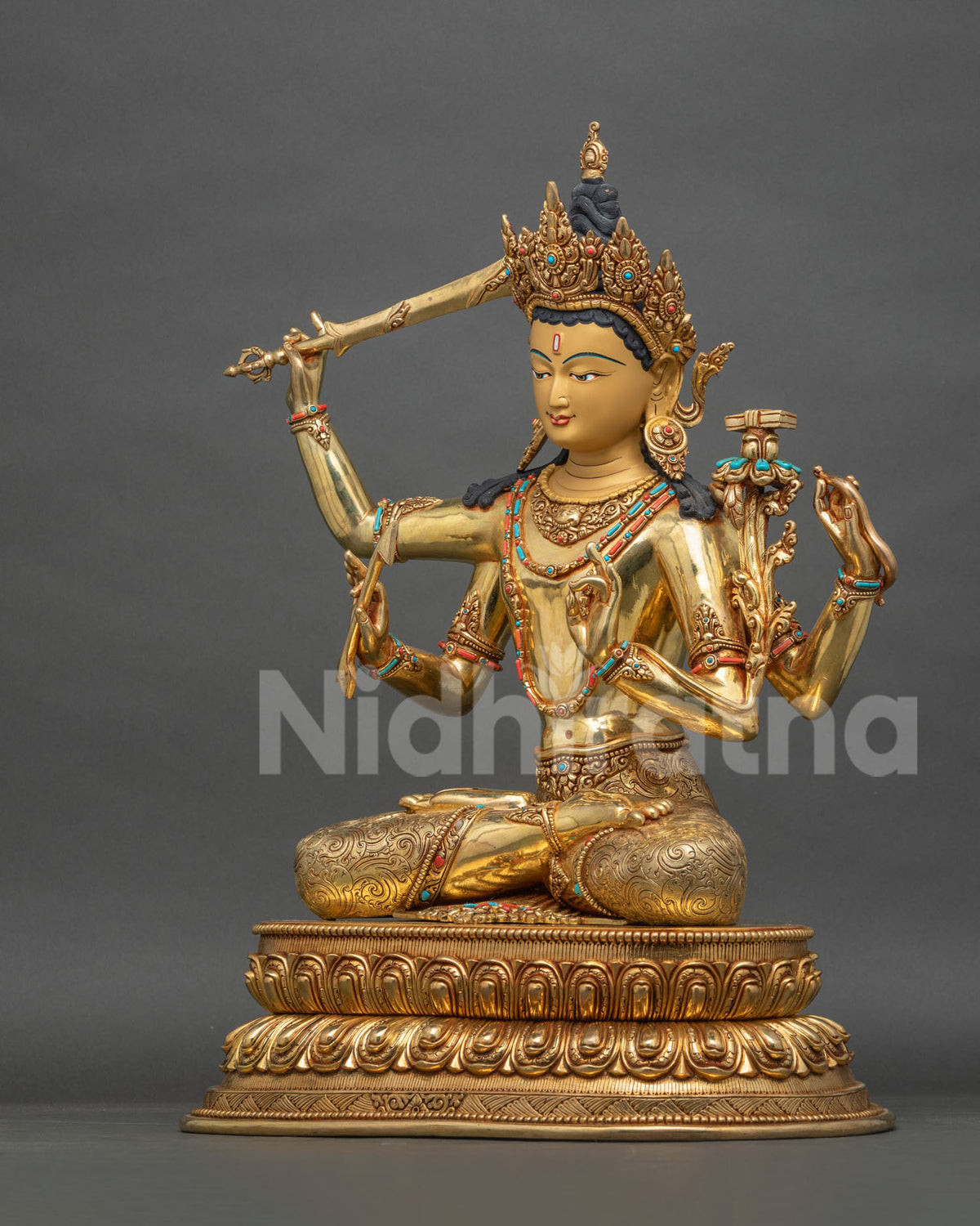 Left side view of seated Maha Manjushri statue with utpala flower and Prajnaparamita Sutra on lotus base