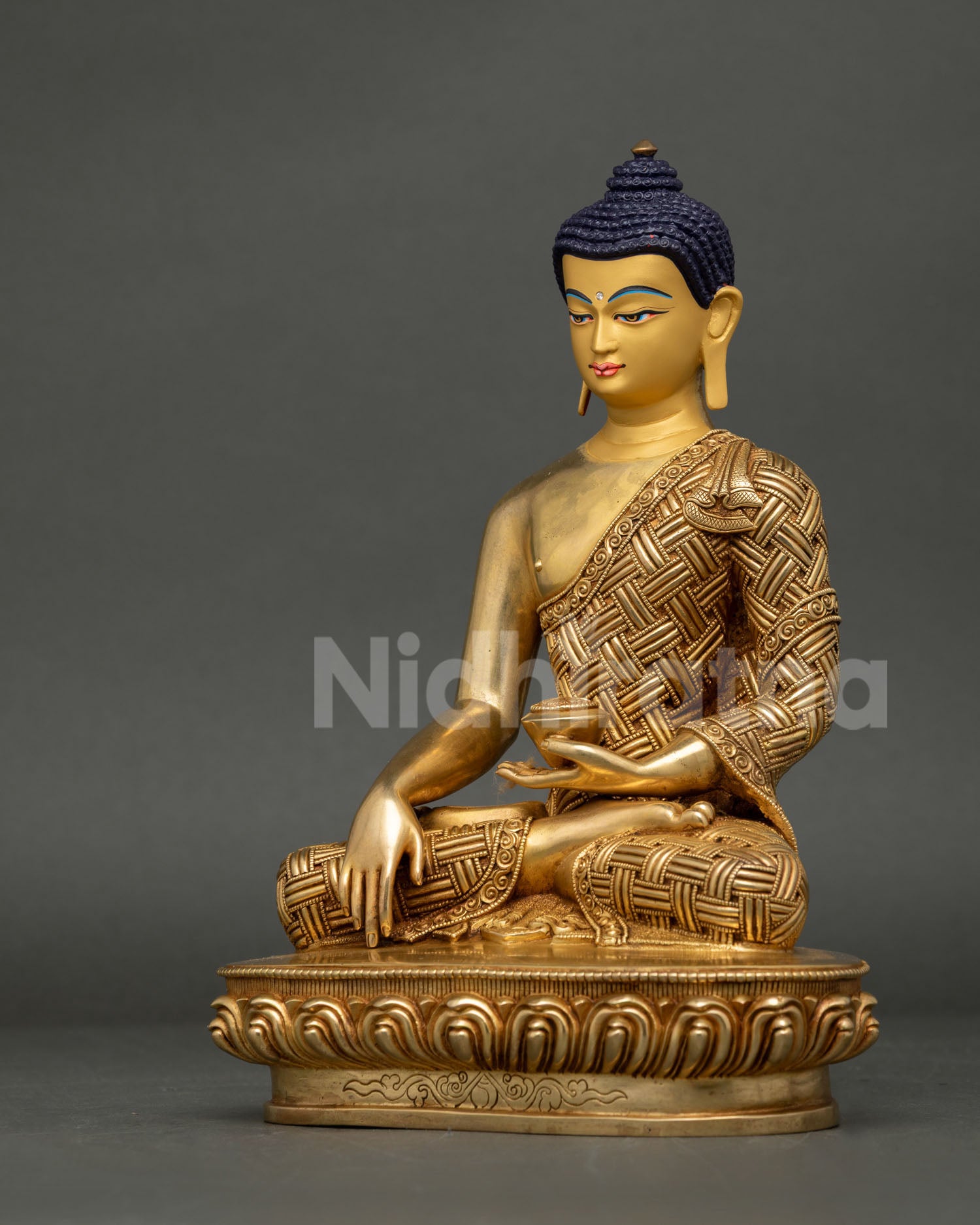 Left-side view of Shakyamuni Buddha statue with intricate repoussé robe and gold-gilded finish