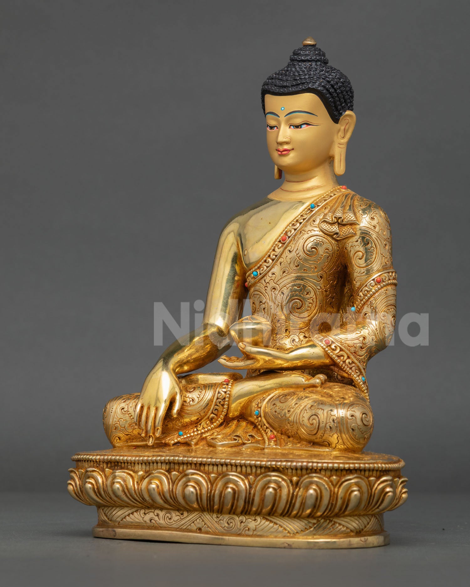 Left side view of the gold fire-gilded Shakyamuni Buddha statue holding a traditional begging bowl.