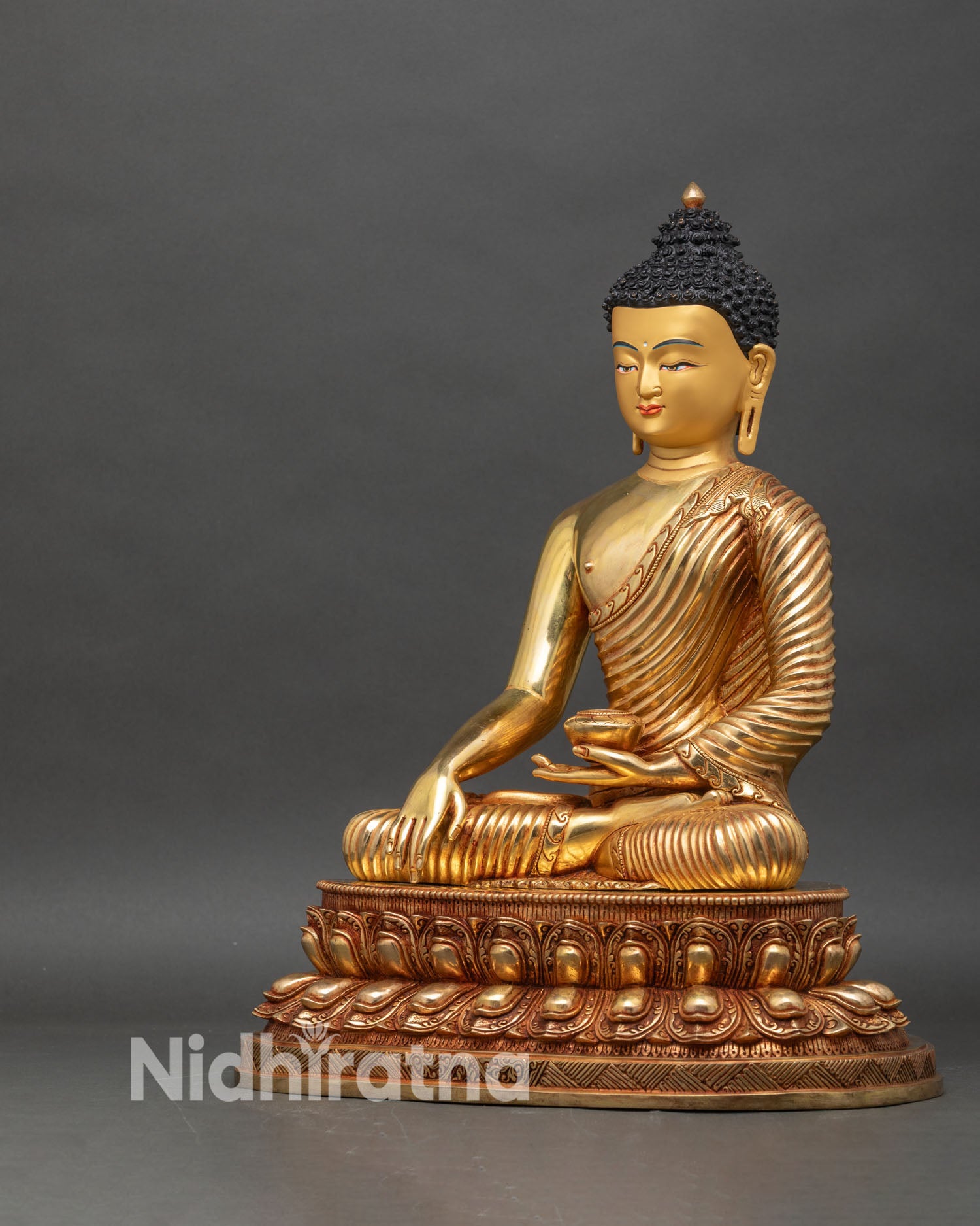 Left side view of Shakyamuni Buddha statue with finely detailed robes and gilded accents