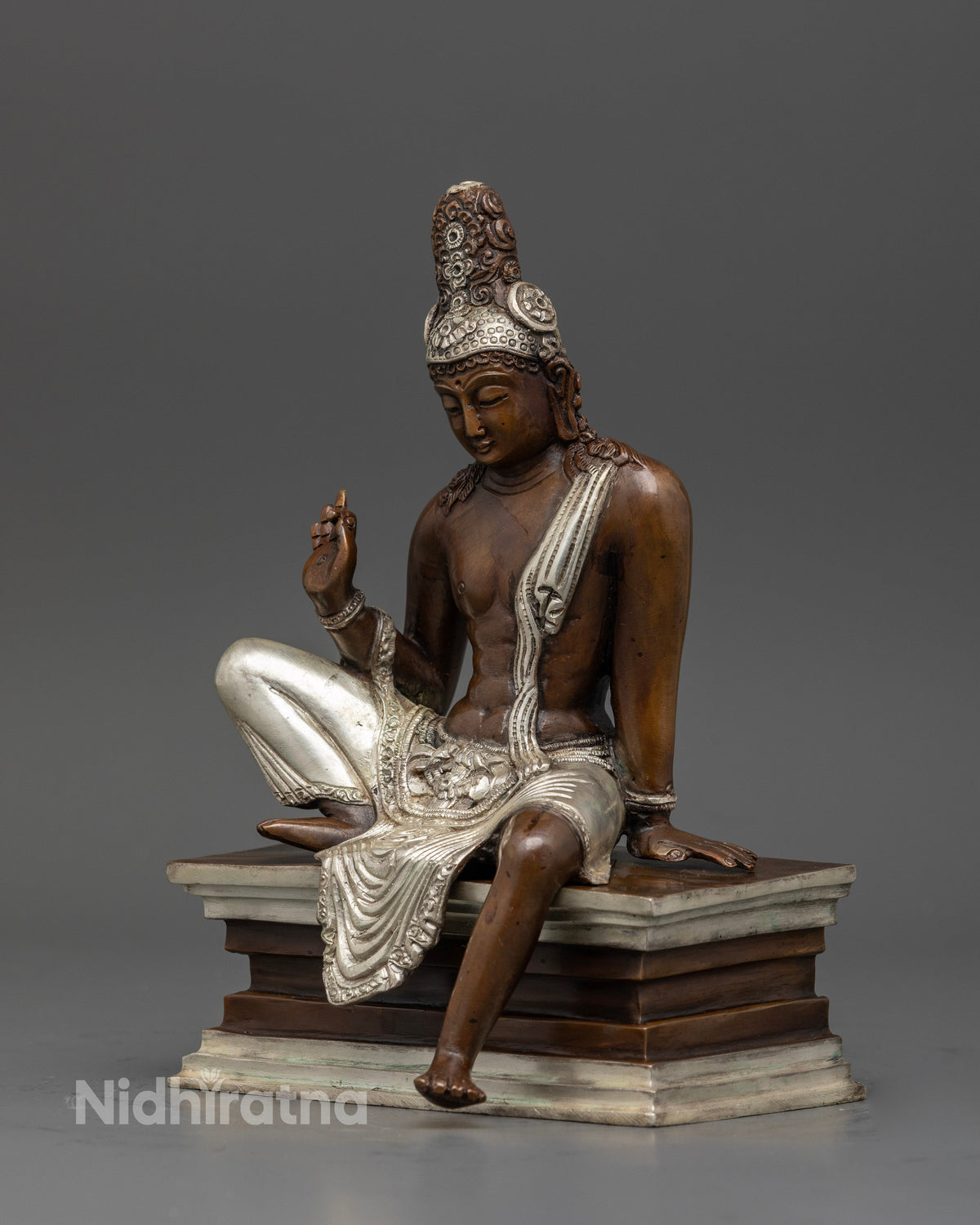 Lokeshwor statue seated on pedestal with silk garment and silver crown.
