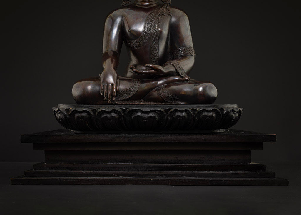 Lower body and carved lotus pedestal of Shakyamuni Buddha statue on dark wooden base