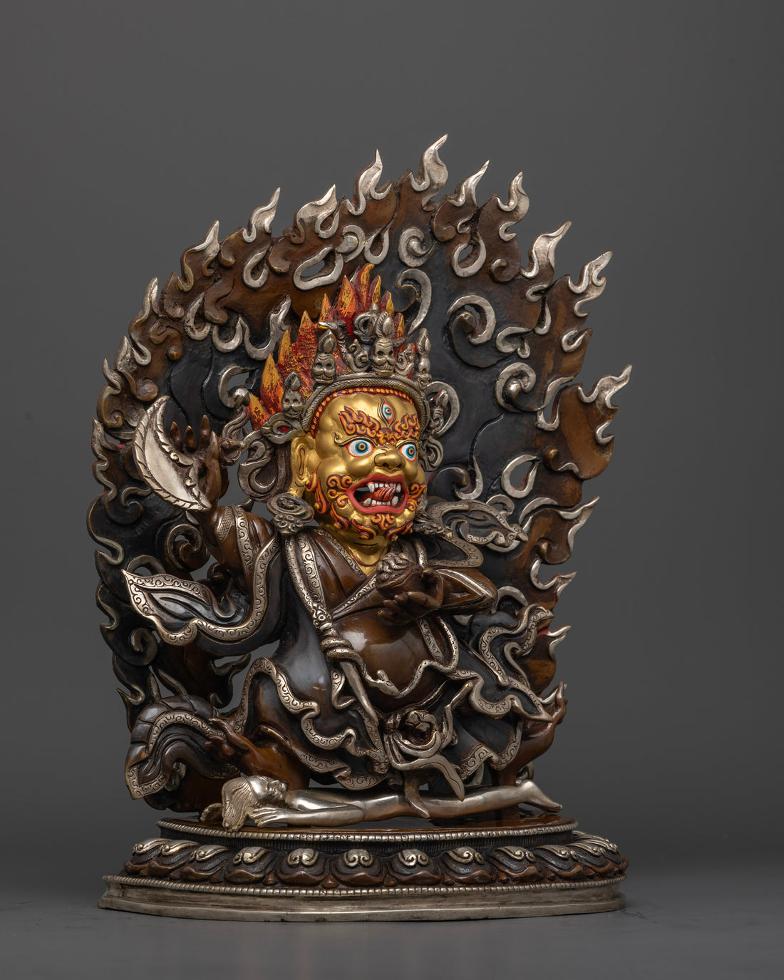 side profile of mahakala bernagchen statue with gold face and silver accents