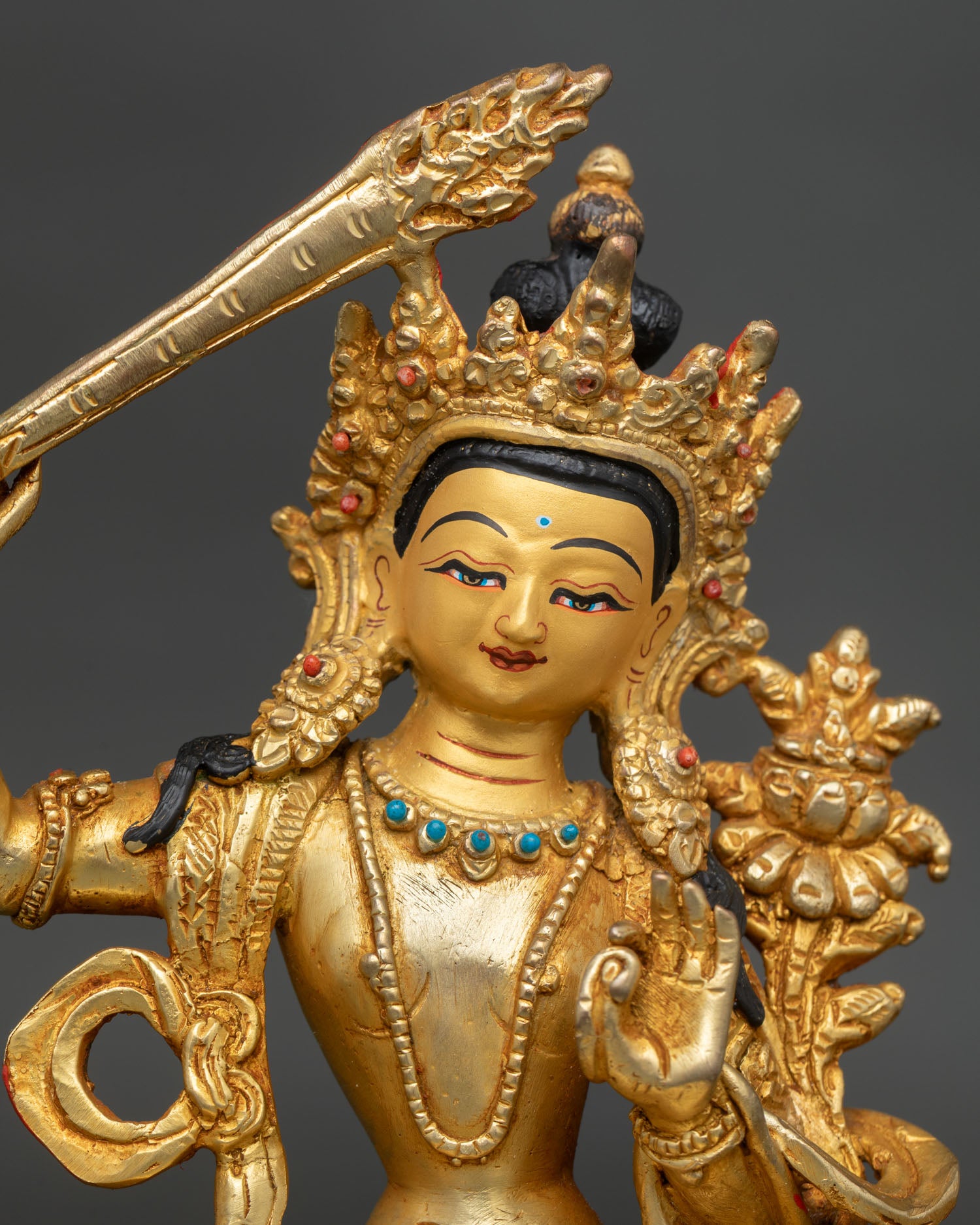 Manjushri bodhisattva face with gold painted details and coral stones.