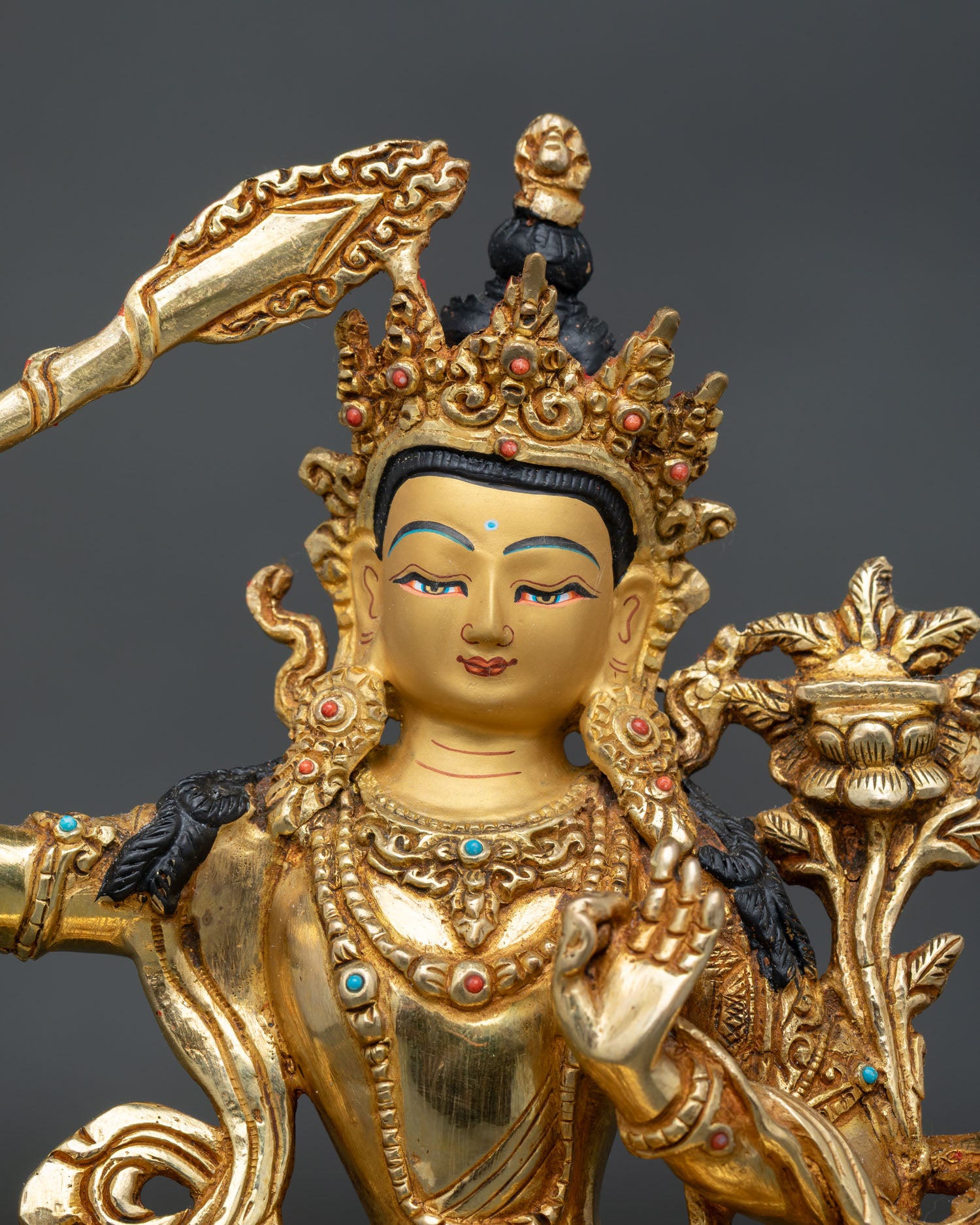 Manjushri bodhisattva face with turquoise and coral stone adornments.