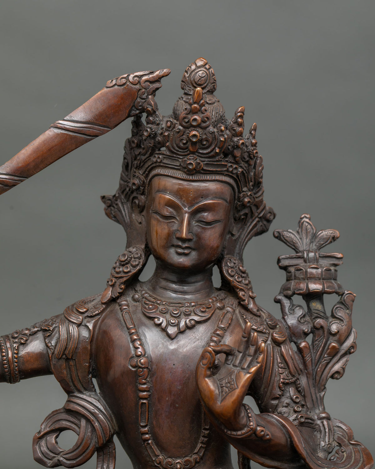 Manjushri Statue close up chemically oxidized copper hand carved lotus pedestal.