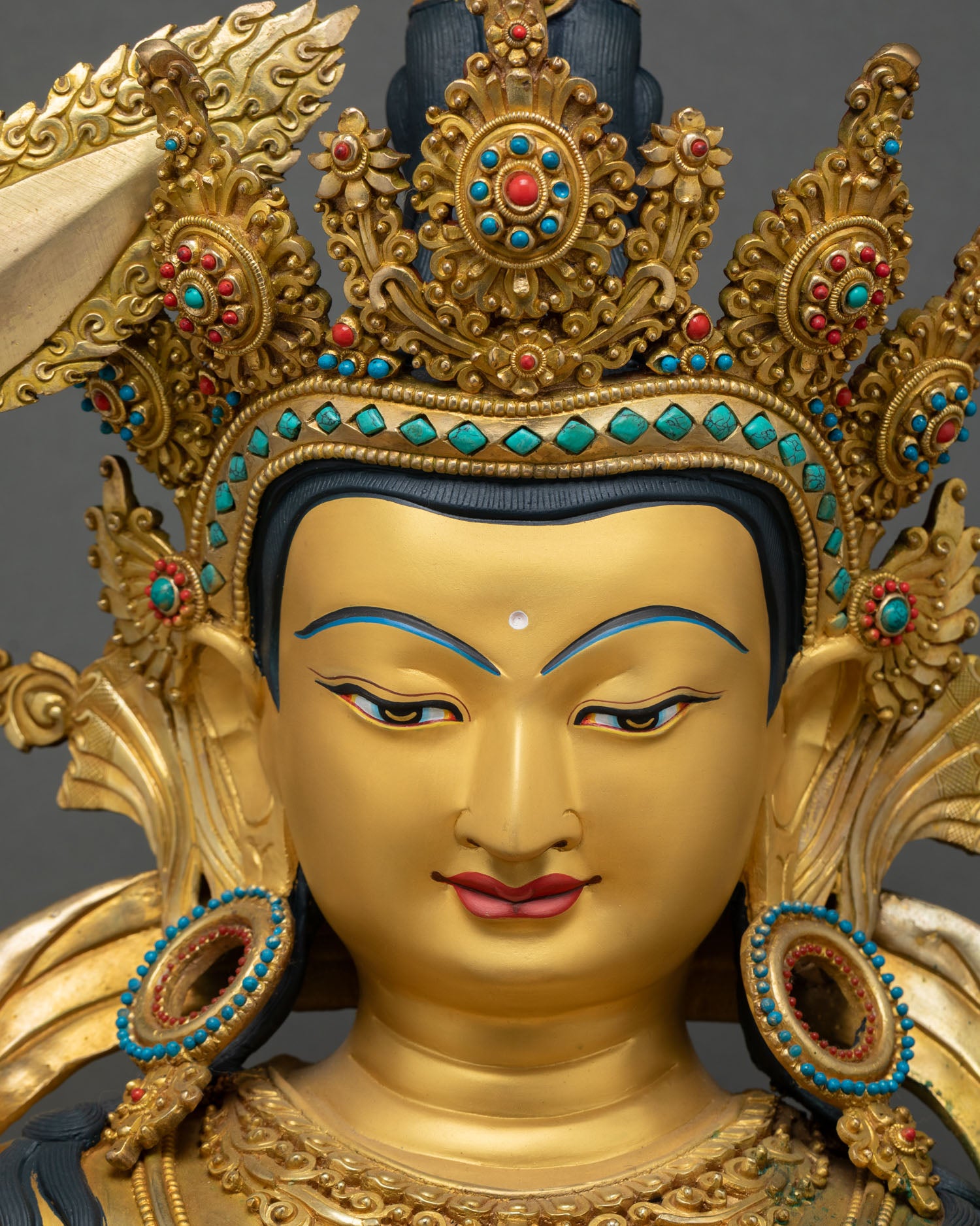 Manjushri statue face detail, gold crown and turquoise earrings Nepal