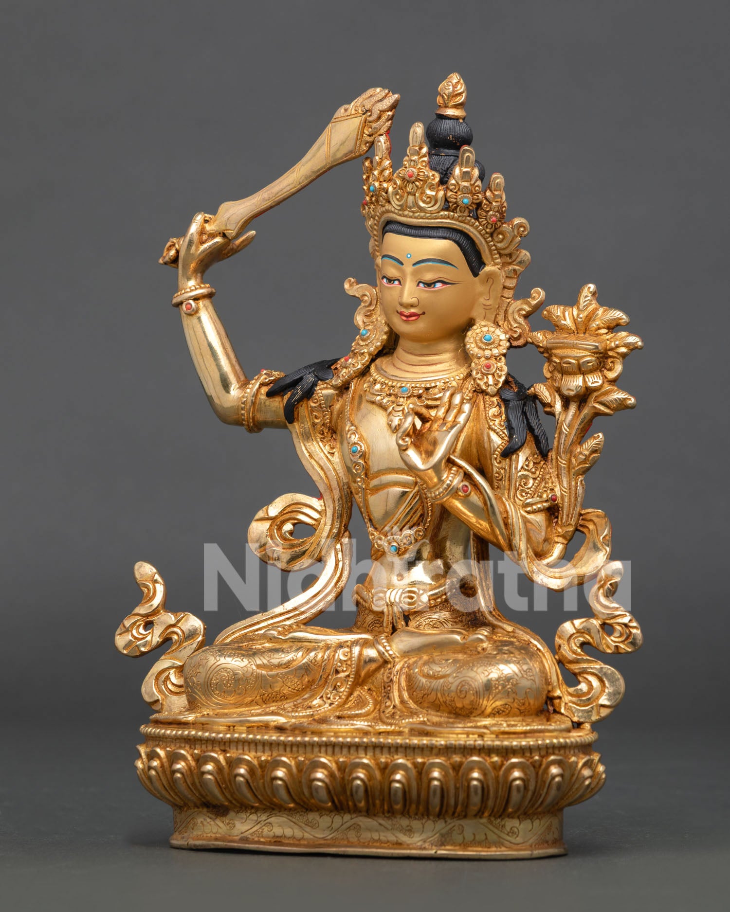 Manjushri Statue holding flaming sword and Prajnaparamita scripture on lotus throne with gold-gilded finish.
