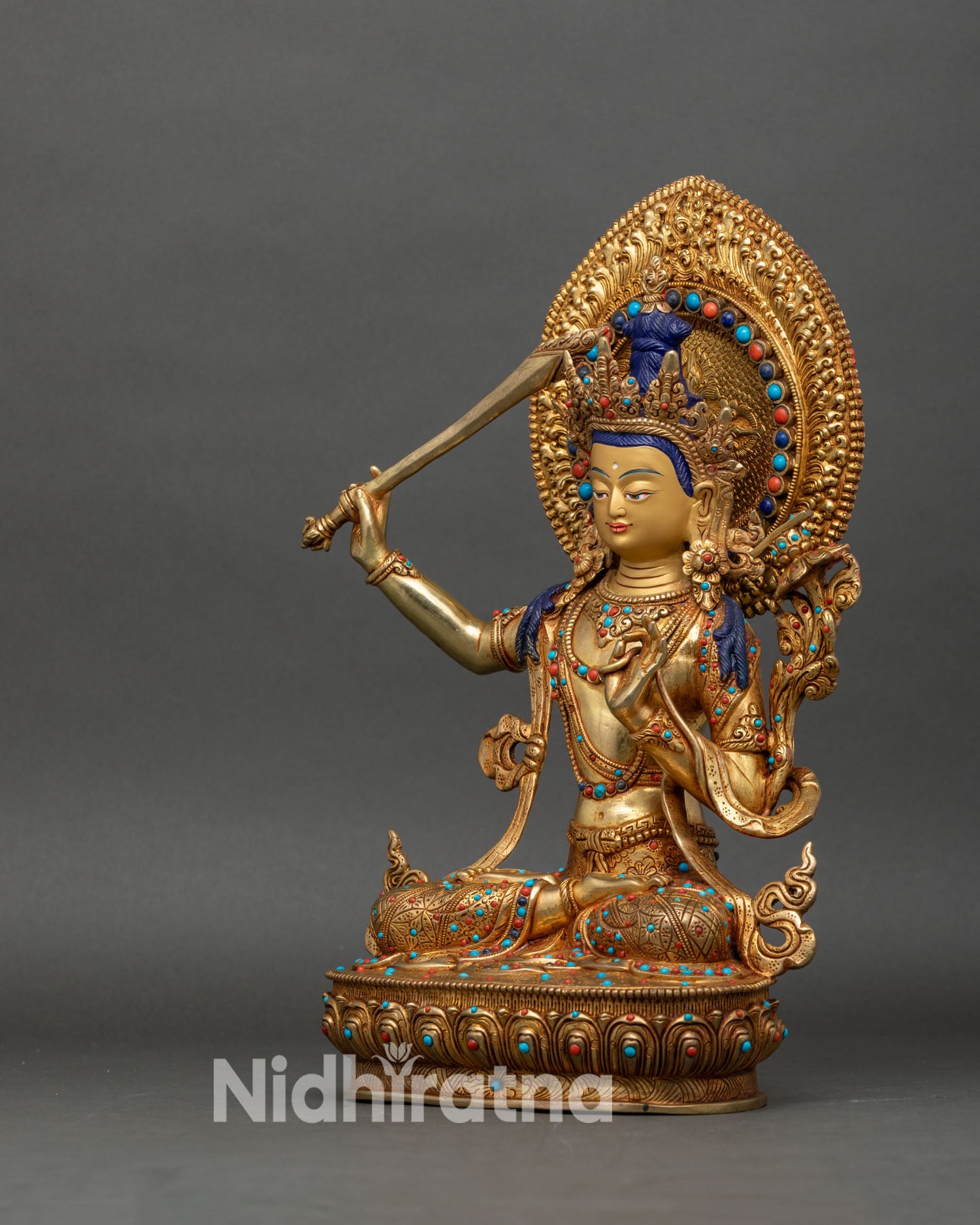left side view of manjushri statue with floral halo, semi precious stone ornaments and gilded robes