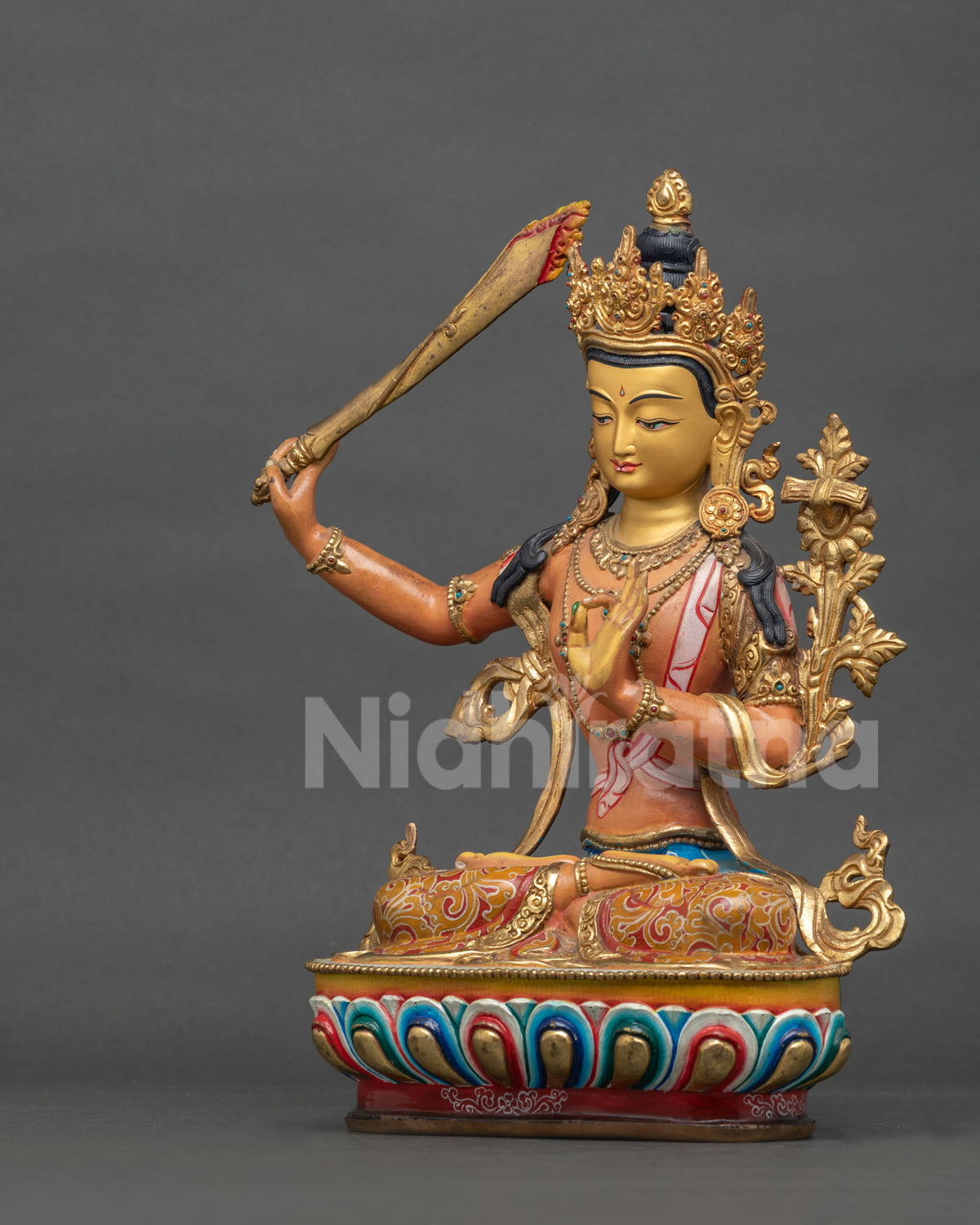 Manjushri statue seated on hand carved lotus pedestal with floral robe motifs.