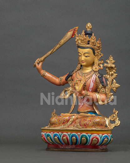 Manjushri statue seated on hand carved lotus pedestal with floral robe motifs.