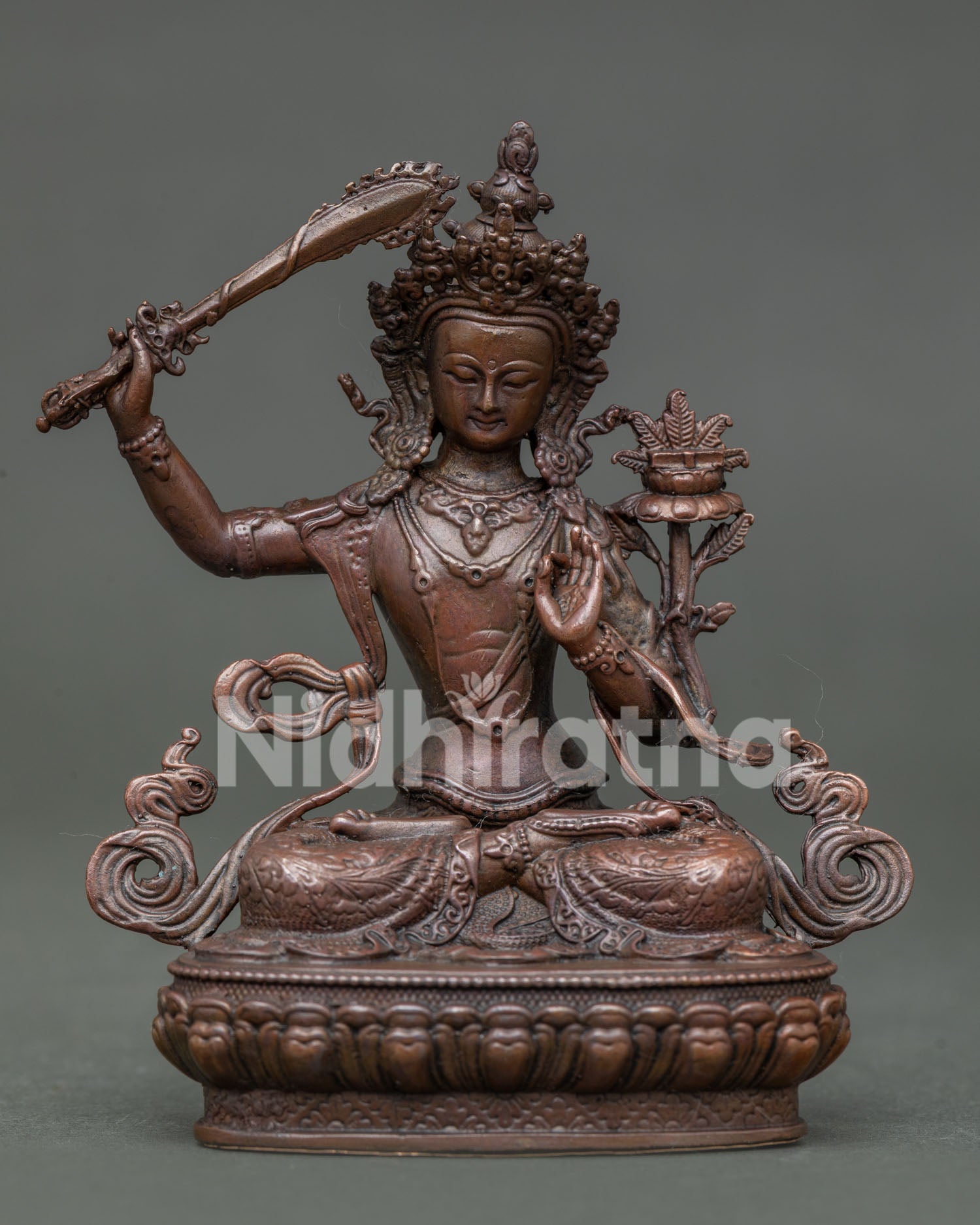 Manjushri statue seated on lotus throne holding flaming sword and prajnaparamita scripture.